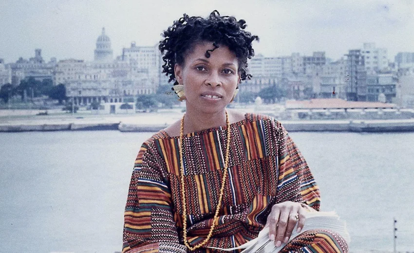 Assata Shakur sitting on the waterfront with the backdrop of the city